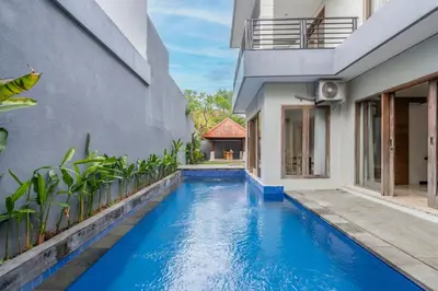 a swimming pool next to a building with a house at Kings Villas Sanur by Moria in Denpasar