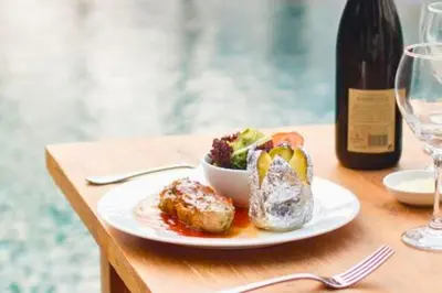 a plate of food on a table with a bottle of wine at Vadjar 1 BR Private Pool Villa in Seminyak