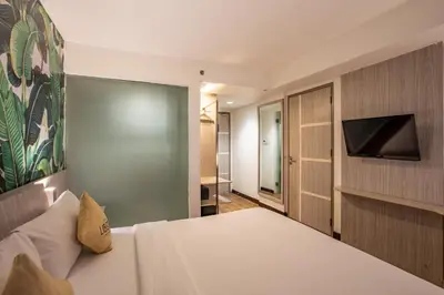 a bedroom with a bed and a flat screen tv at Liberta Seminyak Hotel in Seminyak