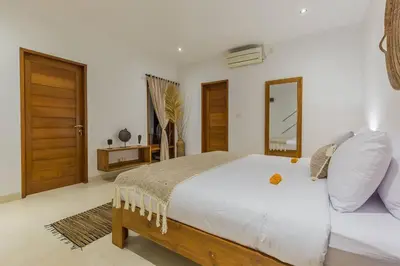a bedroom with a large white bed and a mirror at Villa Lima - 5 bdrs, BBQ, Living room with Ac and private pool in Seminyak