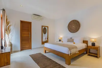 a bedroom with a bed and two tables and a door at Villa Lima - 5 bdrs, BBQ, Living room with Ac and private pool in Seminyak