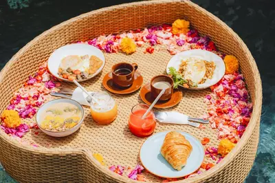 a table with plates of food in a basket with flowers at Taman pangeran villa in Seminyak, 2BR large pool, Prime Location ! in Seminyak