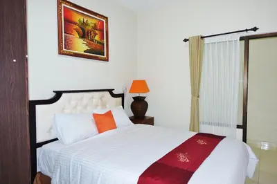 a bedroom with a large white bed with orange pillows at Tuban Torres Accommodation in Kuta