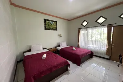 a room with two beds and a window at Taxa Raya Guest House in Legian