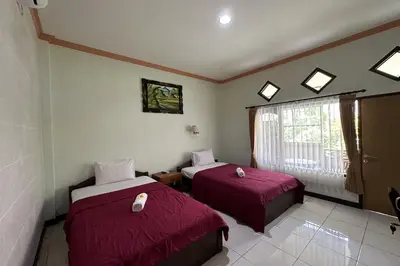 a room with two beds and a window at Taxa Raya Guest House in Legian