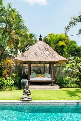 a bed in a gazebo next to a swimming pool at Villa Bliss a Paradise of Three Independent Villas in Canggu