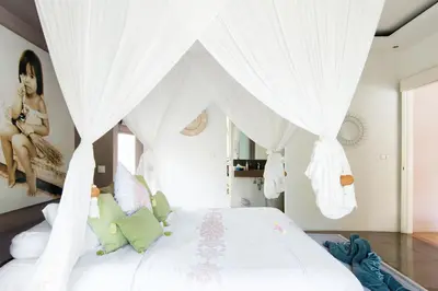 a bedroom with a white bed with white drapes at Villa Bliss a Paradise of Three Independent Villas in Canggu