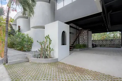 a white building with stairs and a palm tree at The Drupadi Apartments Town House LOLA in Seminyak