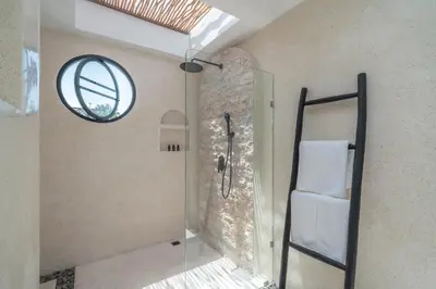 a bathroom with a shower and a round window at Villa Golden Canggu - Modern Chic 2BR Villa Near Finns Recreation Club in Canggu