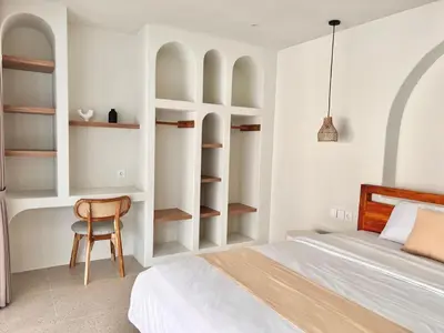 a bedroom with a bed and a chair and shelves at Sofira Villa 2 bedroom in Nusa Dua