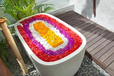 a bathtub covered in flowers sitting next to a bench at 3BR Villa Kita - Minggu Villas-Special Stay Bonus in Seminyak