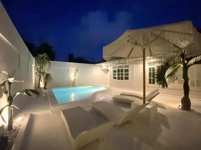 a pool with chairs and an umbrella at night at Villa EL NIS - LEGIAN - 4 Bedroom - 4 Bathroom - Luxury in Legian