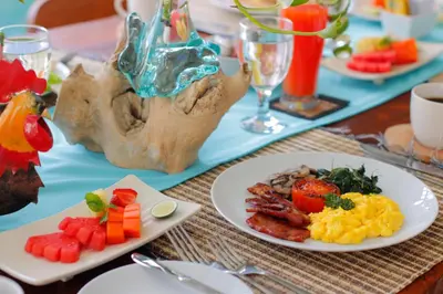 a table topped with plates of food and fruit at Sudha Villa Bali A in Seminyak