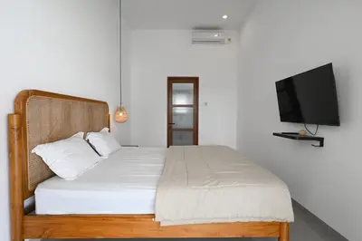 a bedroom with a bed and a flat screen tv at The Samsara Jimbaran Villa in Jimbaran