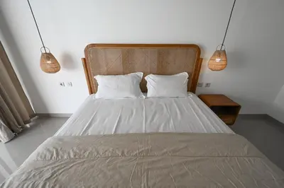 a bedroom with a bed with two pillows and two lights at The Samsara Jimbaran Villa in Jimbaran