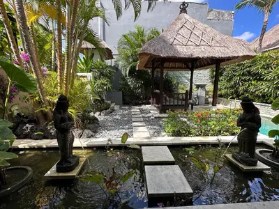 a garden with a pond and a gazebo at Villa Petra Seminyak Bali in Seminyak