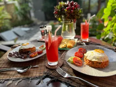 a wooden table with two plates of food and drinks at Villa Petra Seminyak Bali in Seminyak