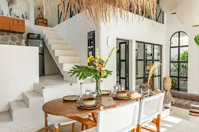 a dining room with a wooden table and white chairs at Casa Toledo 1 Bedroom Seminyak - Kerobokan in Seminyak