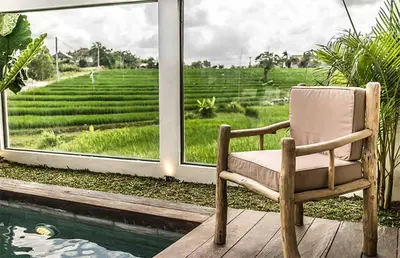 a chair sitting on a porch looking out at a field at Villa Kosibali by Optimum Bali Villas in Kerobokan