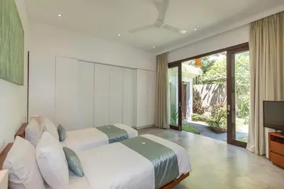 a bedroom with two beds and a flat screen tv at Gajah Villas Bali by Nagisa Bali in Seminyak