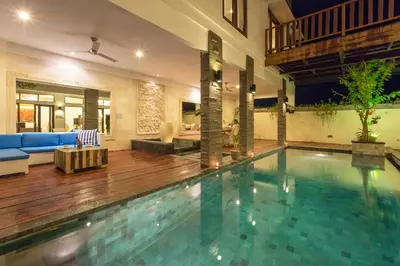 a large swimming pool in a living room with a couch at Villa Club Corner Residence by Nagisa Bali in Canggu