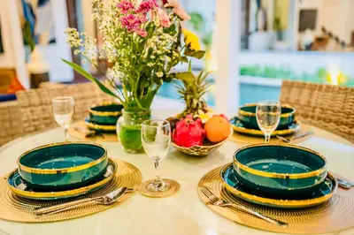 a table with plates and glasses and a vase of flowers at Villa Julissa in Seminyak