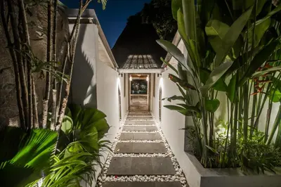 a pathway leading up to a white house with plants at Villa Adagian - Magical 3BR Villa in Umalas in Canggu