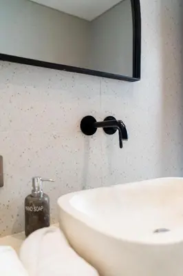 a bathroom sink with a black faucet and a mirror at Villa Arawan - Beautiful 3BR Villa in Kerobokan in Kerobokan