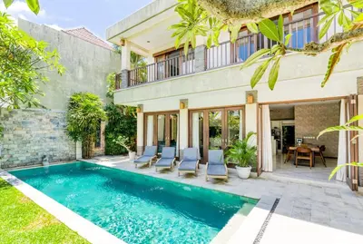 a villa with a swimming pool and a house at Virginia villa 4BR 5min walk to beach with assistant villa and pick up from airport and security in Canggu