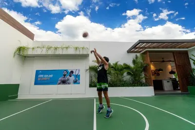 a man hitting a ball on a tennis court at Villa Marlex by Bukit Vista in Seminyak