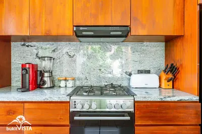 a stove top oven in a kitchen with wooden cabinets at Villa Marlex by Bukit Vista in Seminyak