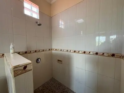 a white tiled bathroom with a shower and a window at Kubu D Kubu Villa - 3 Bedroom - Legian in Legian
