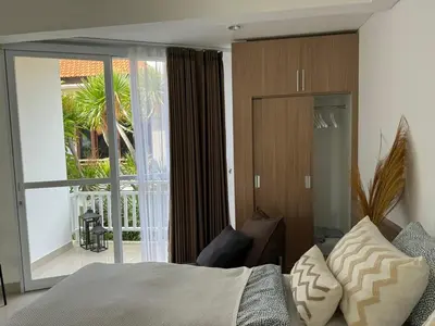 a bedroom with a bed and a sliding glass door at HomelyBali, Cozy studio in Rajapala! in Seminyak