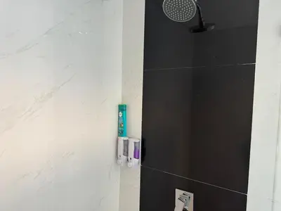 a bathroom with a shower with a toothbrush on the wall at HomelyBali, Cozy studio in Rajapala! in Seminyak