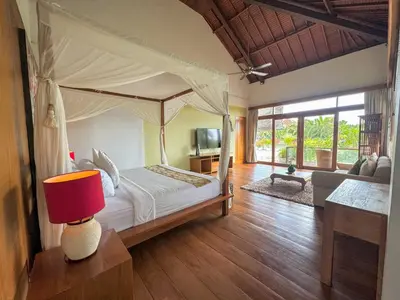 a bedroom with a canopy bed and a living room at Tranquil Classic Balinese Villa in Badung