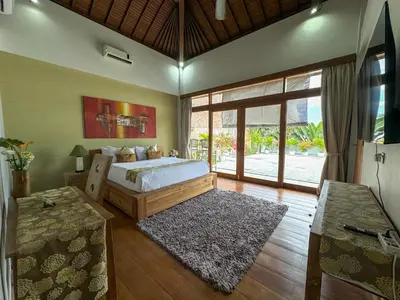 a bedroom with a bed and a large window at Tranquil Classic Balinese Villa in Badung