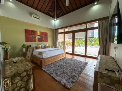 a bedroom with a bed and a large window at Tranquil Classic Balinese Villa in Badung