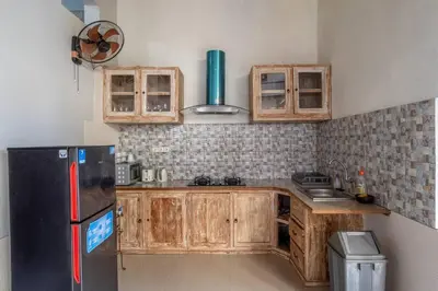a kitchen with wooden cabinets and a black refrigerator at Private 3 Bedroom Villas, 5 mnt to Beach Nusa Dua in Nusa Dua