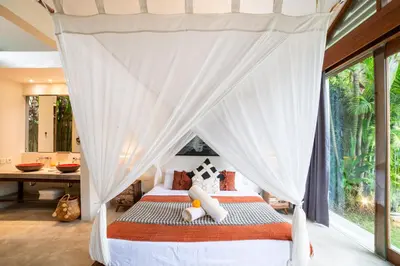a bedroom with a canopy bed with a window at Anggana Villa 3 in Canggu