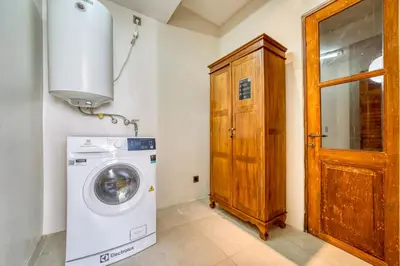 a laundry room with a washing machine and a wooden door at Chic Tranquility Modern yet Timeless 3BD Villa in Canggu