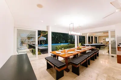 a dining room with a table and chairs and a pool at CassaMia Bali - Spacious Luxury 5 Bedroom Villa in Jimbaran