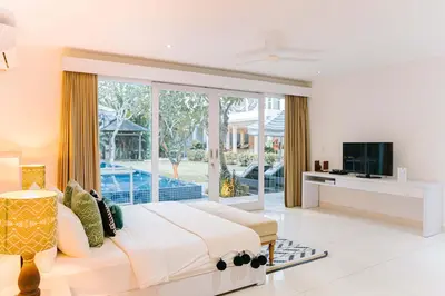 a bedroom with a large bed and a tv in it at CassaMia Bali - Spacious Luxury 5 Bedroom Villa in Jimbaran