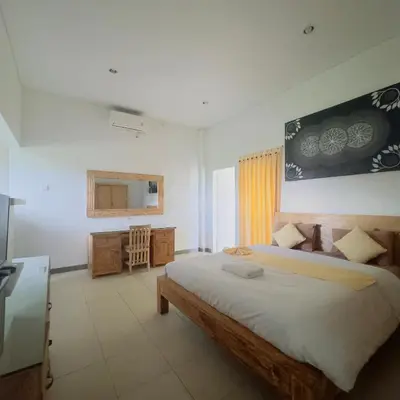 a bedroom with a large bed and a television at Adijaya Rooms in Seminyak