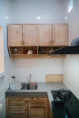 a kitchen with wooden cabinets and a sink at Adijaya Rooms in Seminyak