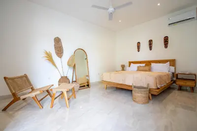 a bedroom with a bed and a mirror and chairs at Kubung 1 - Villa with HUGE Pool and PS5 in Kerobokan