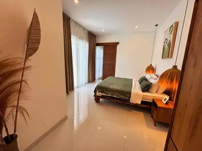 a woman sitting on a bed in a bedroom at Cosy 2bed/2bath villa 5 min to beach in Dalung