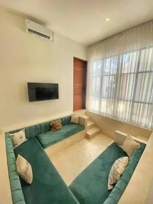 a living room with a green couch and a television at Cosy 2bed/2bath villa 5 min to beach in Dalung