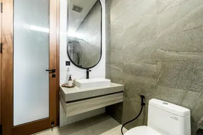 a bathroom with a sink and a mirror and a toilet at Villa Elena by Maheswara in Seminyak