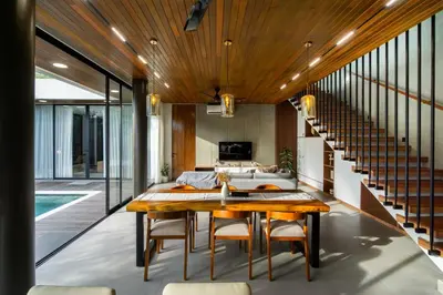 a dining room with a wooden table and stairs at Villa Elena by Maheswara in Seminyak