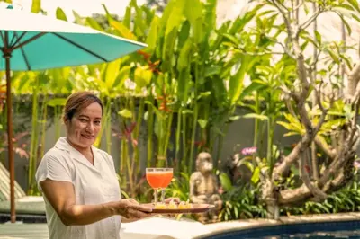 a woman holding a plate of food and a drink at Hazel Azalea 4 BR Private Pool Villa in Seminyak